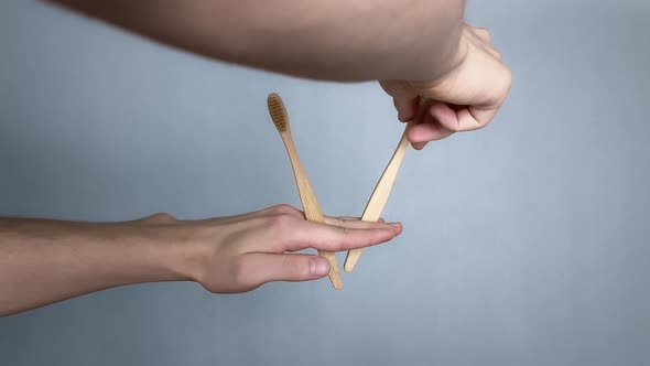 Person puts bamboo toothbrushes in a hand on Gently blue background. Stop
