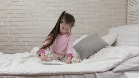 Cute Little Girl Drawing Pictures While Lying on Bed