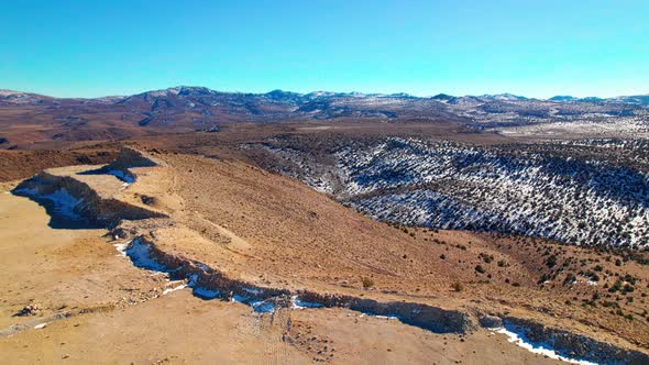 Aerial view over desert mountains landscape with a little snow in Nevada, dry arid climate alt