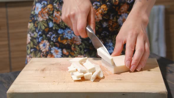 Closeup View Of Slicing Goat Cheese With A Knife On Board