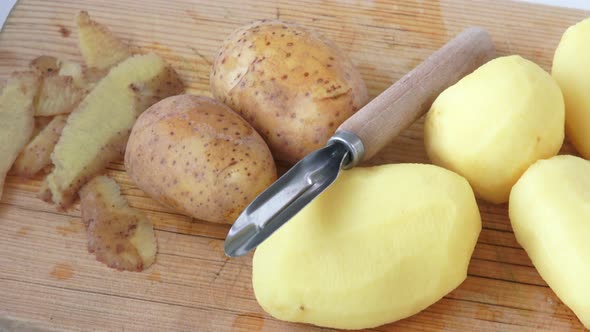 Potato peeler and peelings of tuber, lying on wooden table