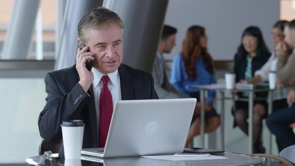 Mature businessman using cell phone in office lobby