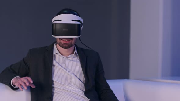 Relaxed Smiling Man in Suit Enjoying Virtual Reality Simulator alt