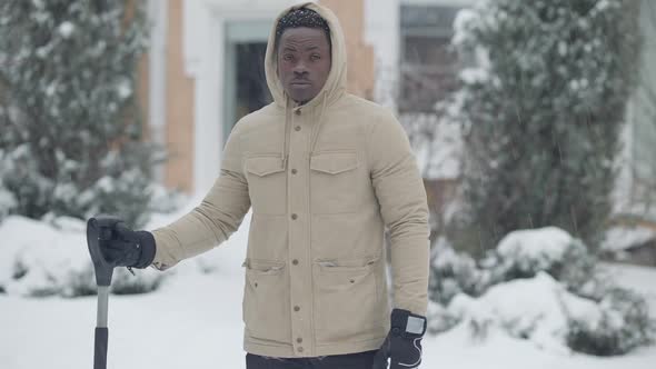Middle Shot of Confident African American Man Standing with Shovel in Snowfall alt