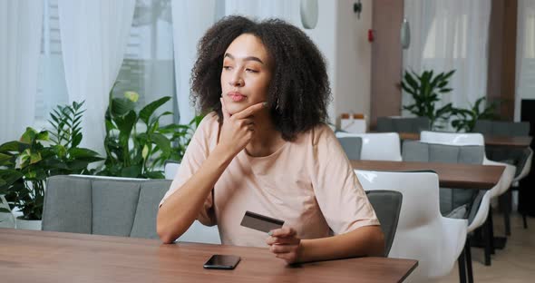 Closeup of Afro American Visitor To Cafe Curly Girl Woman Holding Plastic Credit Bank Card in Her alt