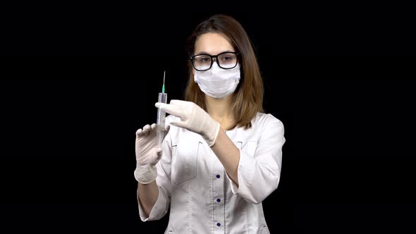 Young Woman Doctor Is Standing with a Syringe Filled with Medication. A Doctor Sprays From a Syringe alt