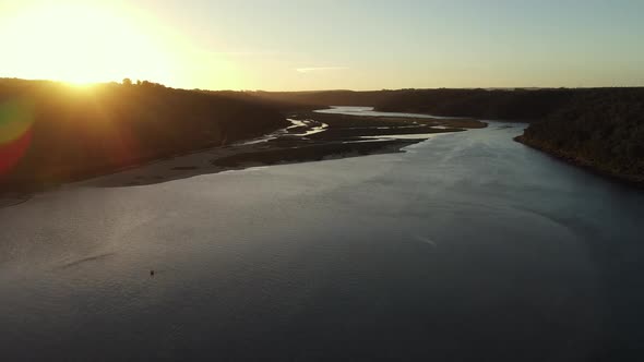 Drone Flying Along Lagoon with Rays From Sunset Reflecting alt