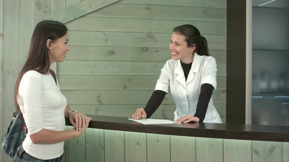 A Spa Receptionist Greeting A Female Customer At The Welcome Desk