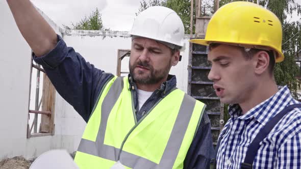 Male Engineers Using Blueprint at Work alt