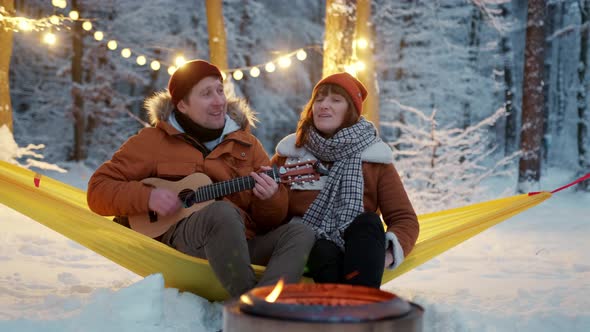 Couple Guy with a Girl Sitting By the Fire with a Singing Fun with a Guitar Winter alt