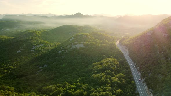 Amazing sunset aerial top drone view of high-speed road between the picturesque mountains