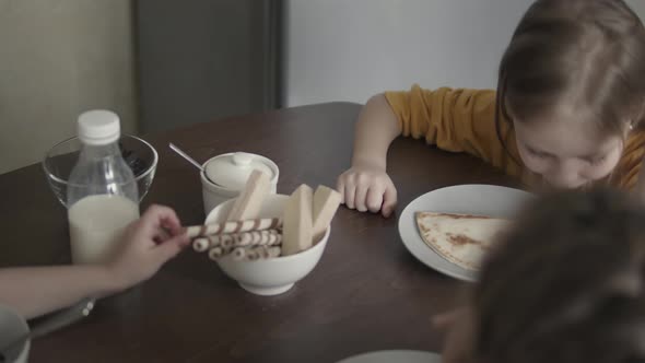 Children in Pajamas Have Breakfast at Home