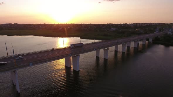 Aerial Shot of a Big Bridge with a Riding Semi-trailer at Golden Sunset in Summer