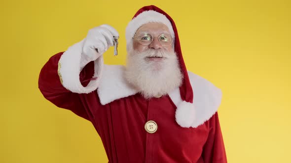 Santa Claus holding keys of new house or apartment on yellow background