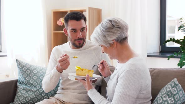 Senior Mother and Adult Son Eating Cake at Home alt