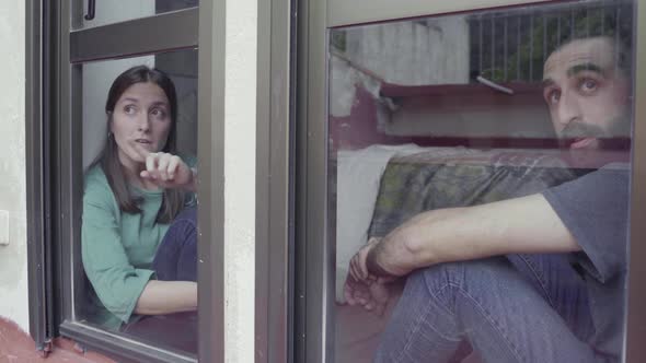 Couple sitting on window sill and looking out of the window