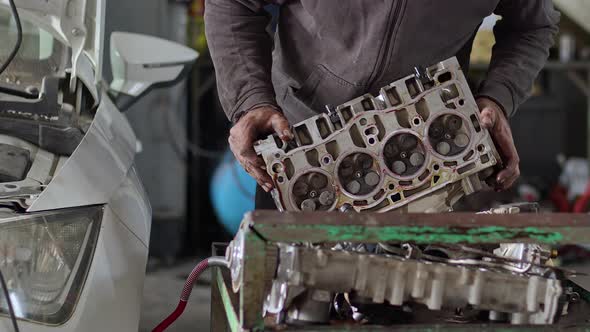 Car Master Repairing Cylinder Head Of Car Engine In Repair Shop 2 alt
