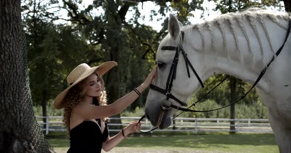 Beautiful Girl In A Hat Stroking A White Horse alt