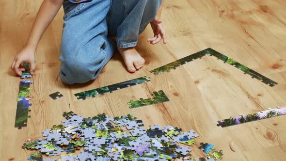 A Beautiful Girl Collects Puzzle Puzzles Sitting on a Wooden Floor