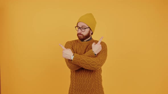 Young Caucasian Man Hesitating Pointing Sideways with Arms Crossed Orange Background Medium Shot alt