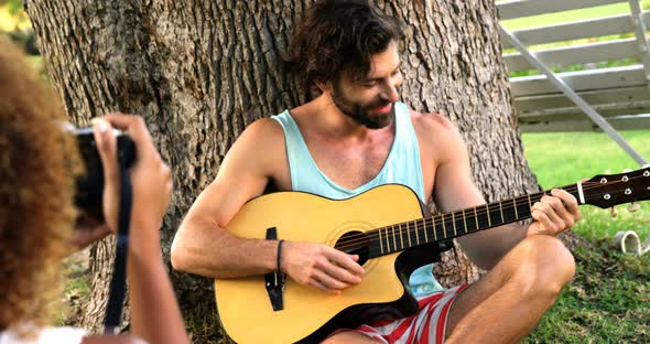 Woman taking a picture of a man playing guitar alt