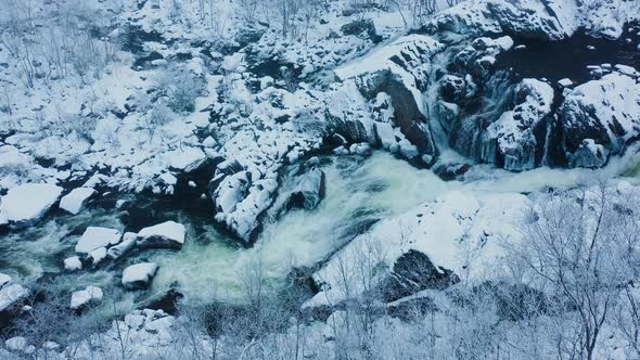 Top down aerial view of the river flow in a snow covered rocky area in winter.