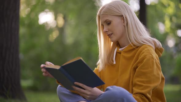 Young Pretty Woman Reads an Adventure Novel with Interest in Nature alt