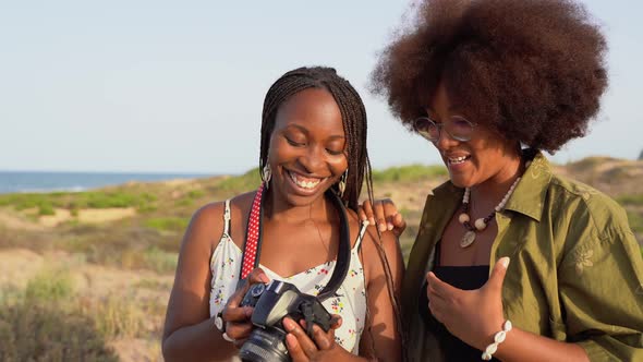 Happy black girlfriends with photo camera in summer nature alt