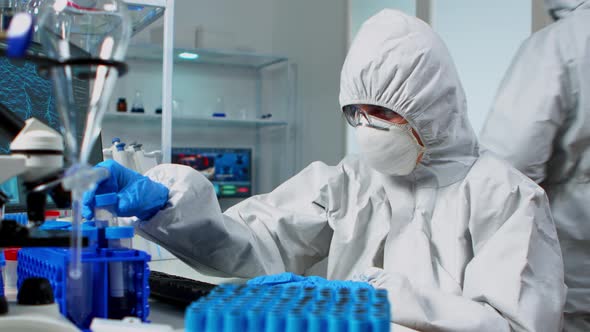 Researcher in Coverall Testing Liquid Sample Using Test Tubes alt