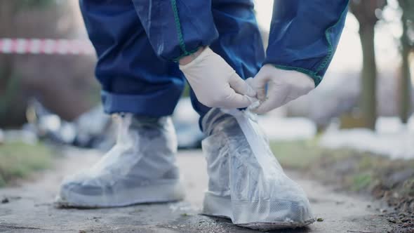 Closeup Unrecognizable Criminologist Tying Shoelaces on Protective Shoes Outdoors alt