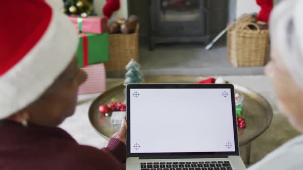 Two happy diverse senior woman on video call on laptop with copy space at christmas time alt
