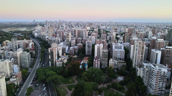 Aerial pan right of Belgrano neighborhood buildings and parks at sunset with Rio de la Plata river i alt