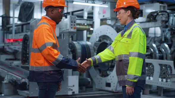 Businesspeople Shaking Hands at Machinery Plant alt