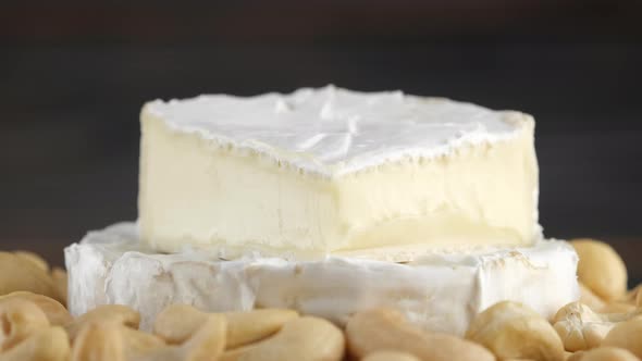 camembert or brie cheese with cashews close up, rotation. Soft, creamy cheese. 4K UHD video alt