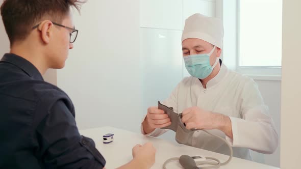 A Doctor in Latex Gloves Using a Pulse Oximeter Measures the Level of Oxygen in the Patient's Blood alt