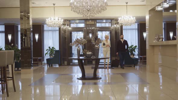 Extreme Wide Shot of Caucasian Man and Woman with Travel Bag Entering Luxurious Hotel Vestibule and alt