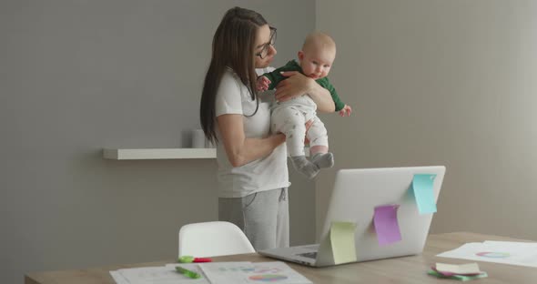 The Mother Is Taking a Break From Work and Carrying the Baby in Her Arms alt