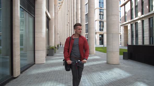 Stylish Man Riding Electric Kick Scooter in Downtown alt