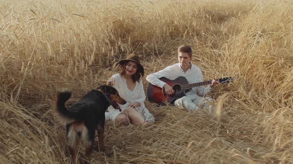 Couple in Love Man and Woman are Playing with Dog in the Field of Spikelets Handheld Shot alt
