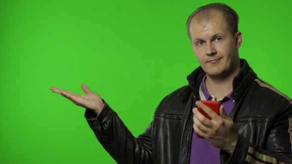Rocker Man Showing Side Advertising Area, Using Smartphone, Pointing at Wall for Your Text, Logo alt