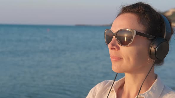 Woman in headphones looks at the dawn.  alt