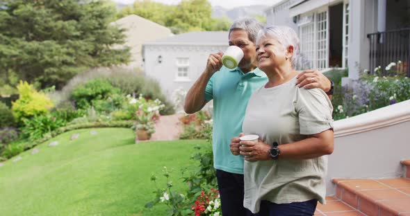 Video of relaxed biracial senior couple drinking coffee in garden alt