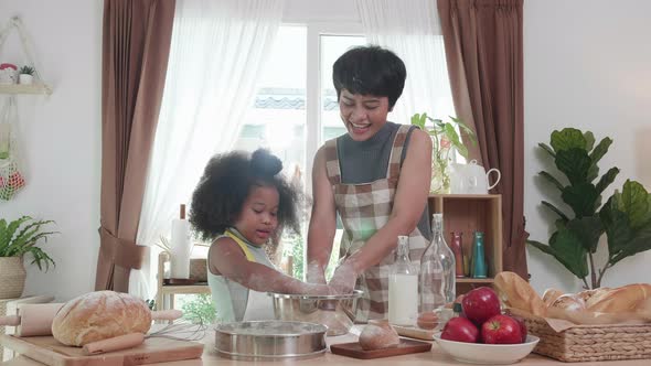 Happy mixed race family having fun in kitchen while threshing flour together for cookies at home