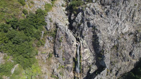 Aerial descending towards magnificent waterfall High stone Cliff - Mizarela alt