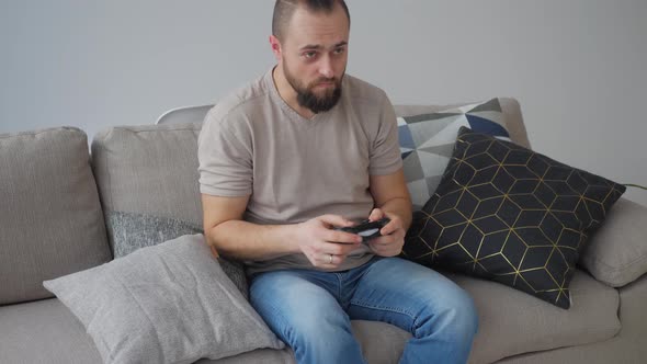 Portrait of a young man playing video games at home, losing and being disappointed and frustrated wi alt