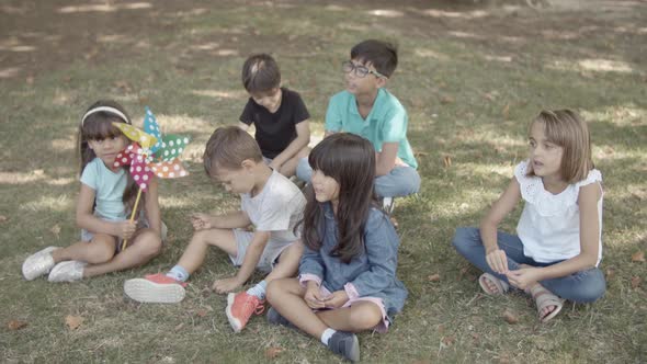 Multiethnic Children Sitting on Grass in Park Together alt