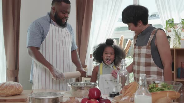 Happy black family having fun dancing and cooking together inkitchen at home