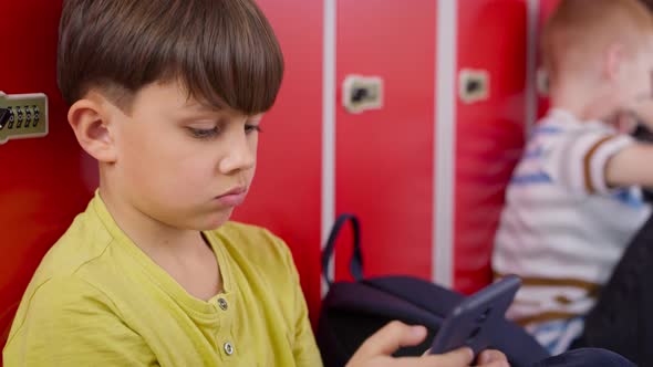 Close up video of schoolboy using smartphone in school corridor. Shot with RED helium camera in 8K. alt