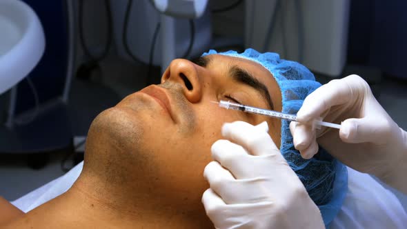 Doctor inserting facial injection on male patient face alt