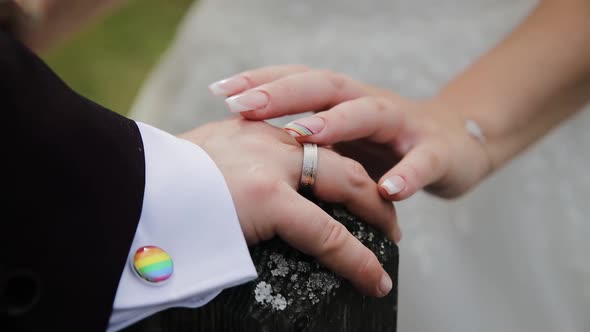 LGBT wedding. Close up of newlyweds hands with pride rainbow emblem elements. Nail rainbow manicure alt
